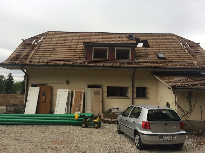 Casa amb el teulat de fusta desmuntat i les portes de fusta amuntegades al costat